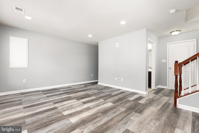 empty room with baseboards, visible vents, stairway, wood finished floors, and recessed lighting