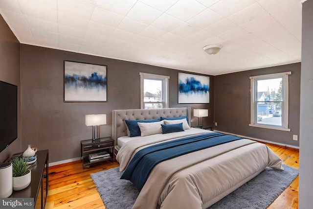 bedroom featuring multiple windows, baseboards, and wood finished floors