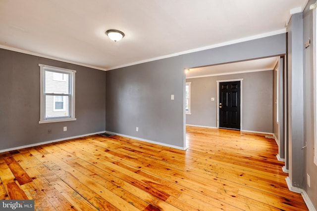 spare room with ornamental molding, light wood-style flooring, and baseboards