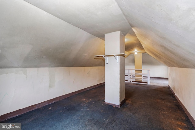 additional living space featuring baseboards, vaulted ceiling, and dark colored carpet