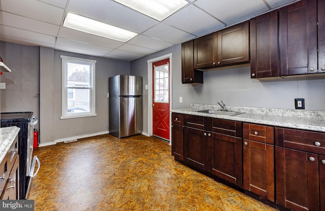 kitchen with light stone counters, stainless steel appliances, a paneled ceiling, visible vents, and a sink