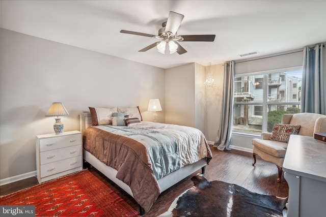 bedroom with a ceiling fan, dark wood-style flooring, visible vents, and baseboards