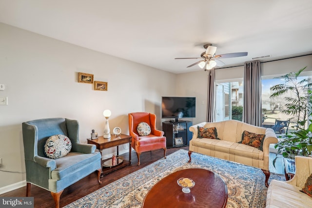 living room featuring dark wood-style floors, visible vents, ceiling fan, and baseboards