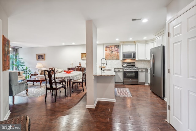 kitchen featuring visible vents, appliances with stainless steel finishes, open floor plan, white cabinetry, and a sink