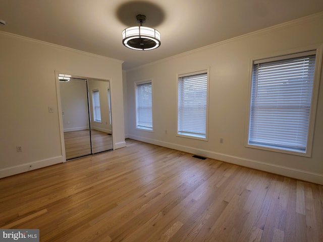 interior space featuring crown molding, light wood-type flooring, visible vents, and baseboards