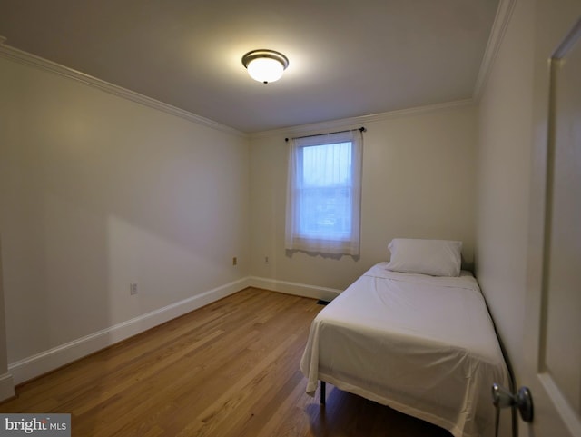 bedroom with ornamental molding, baseboards, and wood finished floors