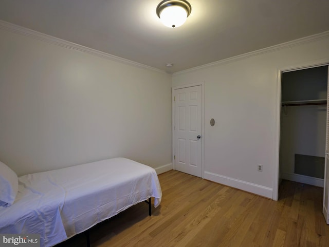 bedroom featuring ornamental molding, light wood-type flooring, and baseboards