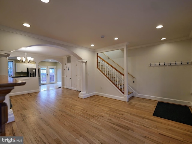 unfurnished living room with arched walkways, stairway, light wood-type flooring, and recessed lighting