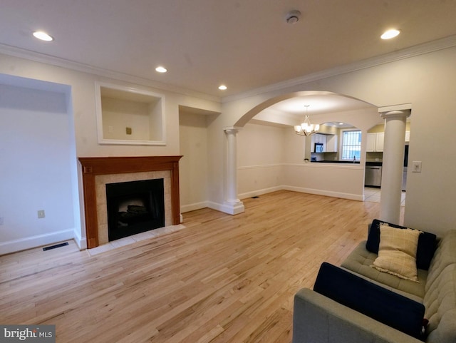 living room with light wood-style floors, arched walkways, visible vents, and decorative columns