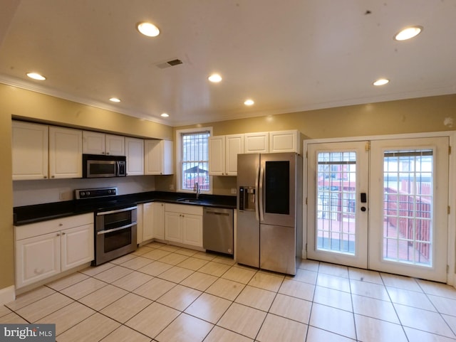 kitchen with white cabinets, dark countertops, appliances with stainless steel finishes, french doors, and a sink