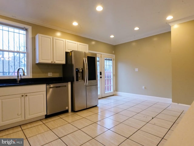 kitchen featuring crown molding, dark countertops, appliances with stainless steel finishes, white cabinetry, and a sink