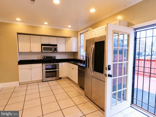 kitchen featuring crown molding, appliances with stainless steel finishes, a sink, and white cabinets