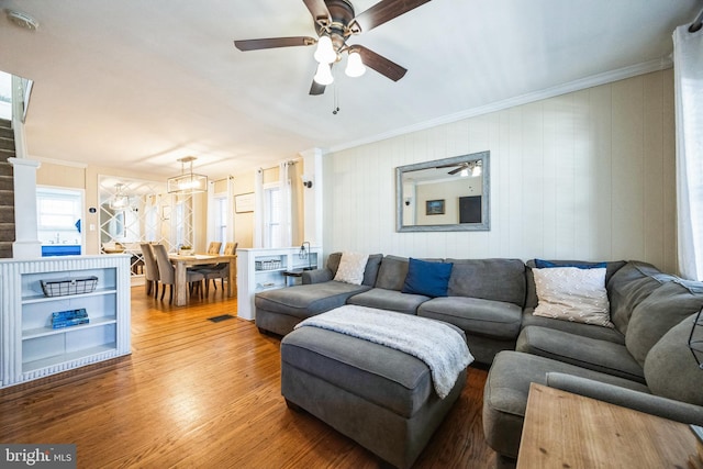 living room featuring wood finished floors, a ceiling fan, and crown molding