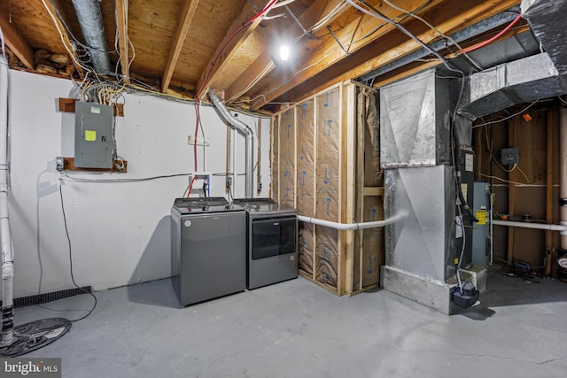 unfinished basement with electric panel, heating unit, and separate washer and dryer