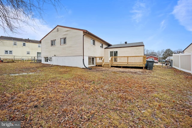 back of house with fence, a deck, and a lawn