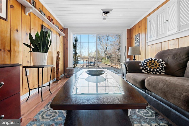 living area featuring ornamental molding, wood walls, and wood finished floors