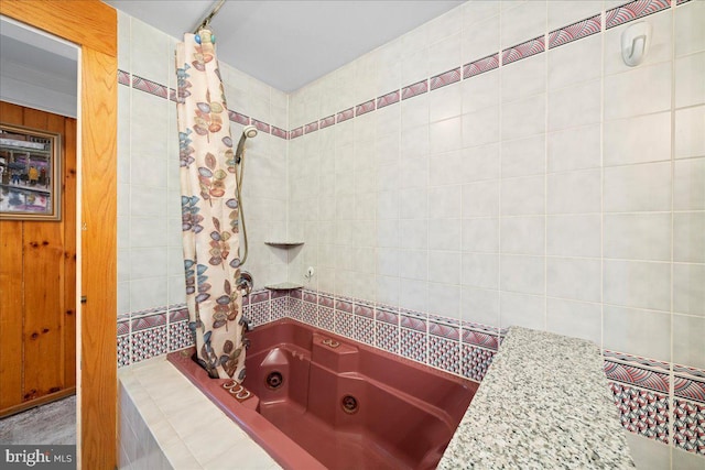 bathroom with a combined bath / shower with jetted tub and tile walls