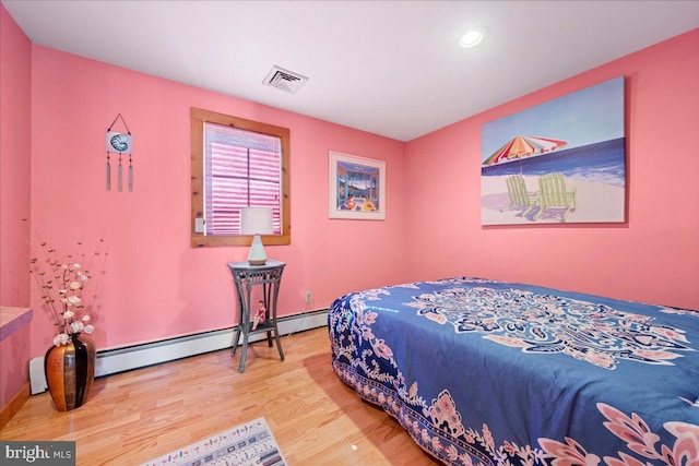 bedroom featuring visible vents, baseboard heating, and wood finished floors