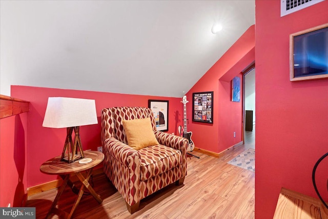 living area featuring vaulted ceiling, wood finished floors, visible vents, and baseboards