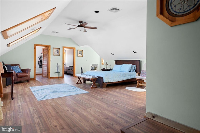 bedroom featuring lofted ceiling with skylight, visible vents, and wood finished floors