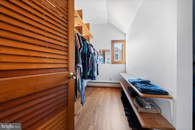 spacious closet featuring lofted ceiling, baseboard heating, and wood finished floors