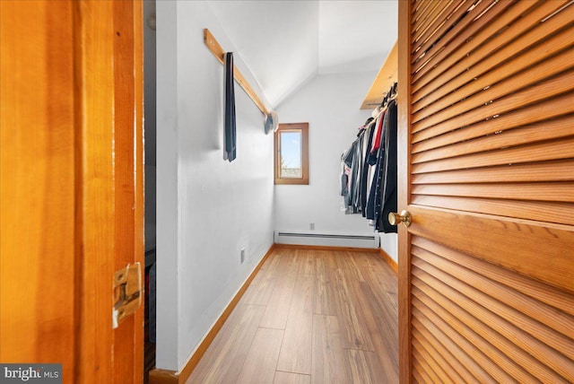 walk in closet featuring light wood-style flooring, vaulted ceiling, and baseboard heating