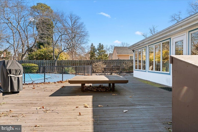 wooden terrace with outdoor dining area, a fenced backyard, and a grill