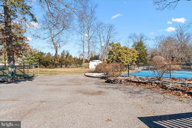 exterior space with an outdoor structure, fence, a storage shed, and a swimming pool