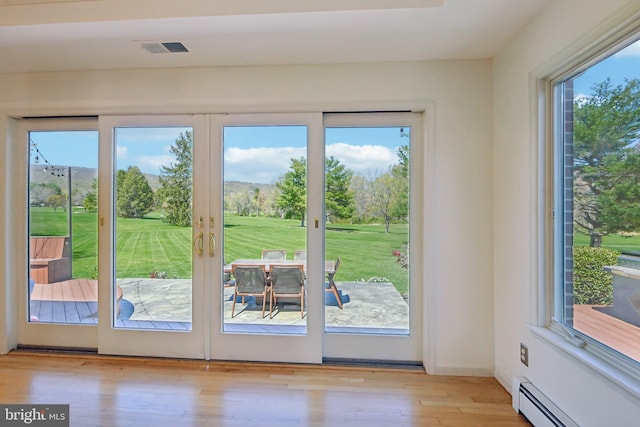 doorway to outside featuring wood finished floors, a baseboard heating unit, and visible vents