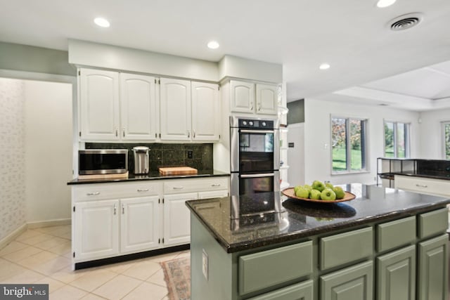 kitchen featuring white cabinets, visible vents, appliances with stainless steel finishes, decorative backsplash, and green cabinetry