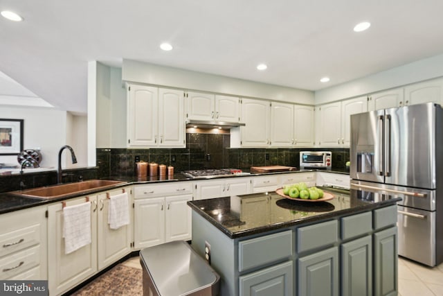 kitchen featuring stainless steel appliances, under cabinet range hood, white cabinets, and a sink