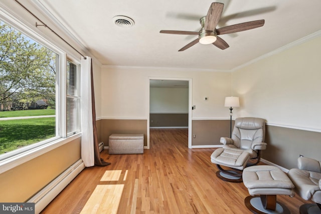 sitting room with visible vents, a wealth of natural light, light wood-type flooring, and baseboard heating