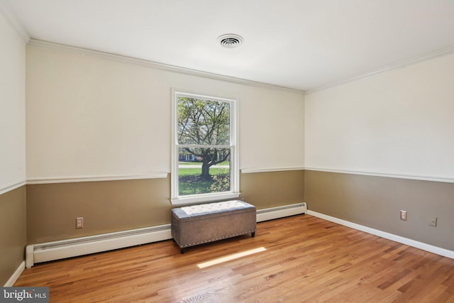 empty room featuring baseboard heating, crown molding, wood finished floors, and visible vents