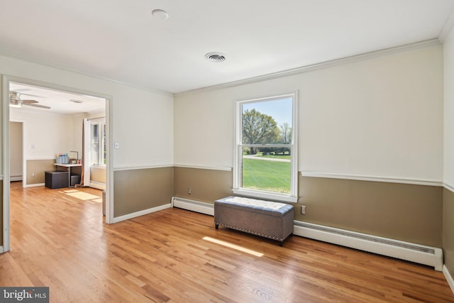 empty room featuring crown molding, a baseboard radiator, and light wood-style flooring