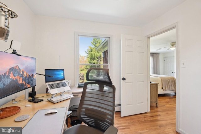 office space with baseboard heating, light wood-type flooring, and ceiling fan