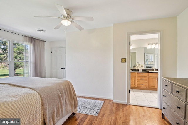 bedroom with baseboards, light wood-style flooring, connected bathroom, visible vents, and ceiling fan