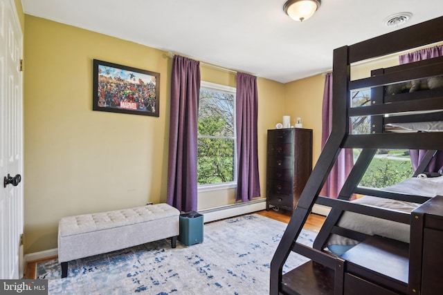 bedroom featuring a baseboard radiator, visible vents, baseboards, and wood finished floors