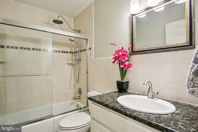 bathroom with tile walls, vanity, toilet, bath / shower combo with glass door, and backsplash