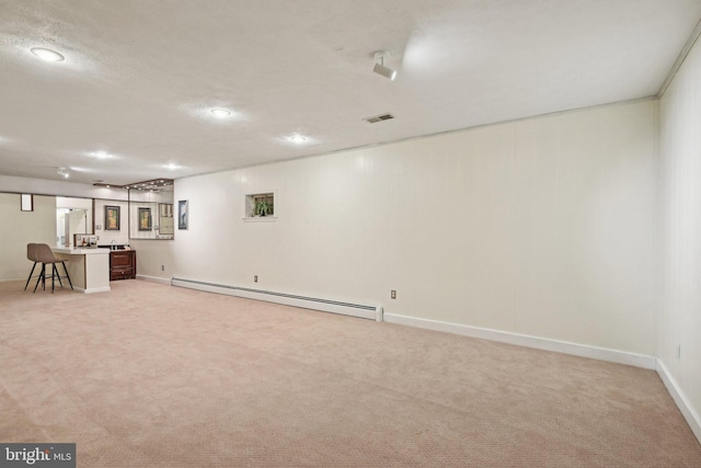finished basement with visible vents, a baseboard radiator, light carpet, and baseboards
