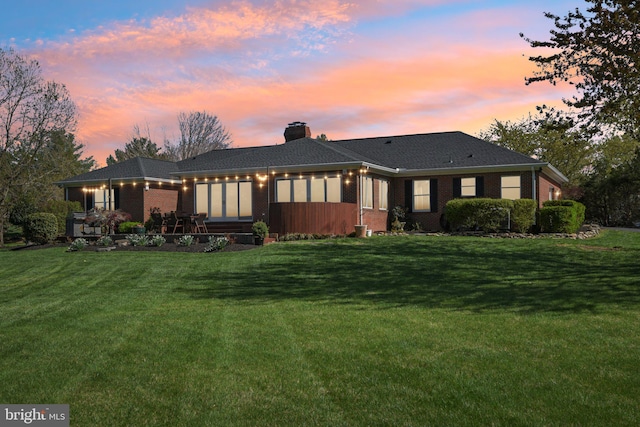 back of property with brick siding, a yard, and a chimney