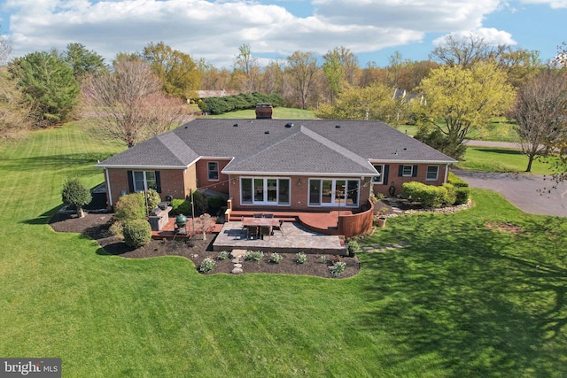 rear view of property featuring brick siding, a chimney, a yard, and a patio area