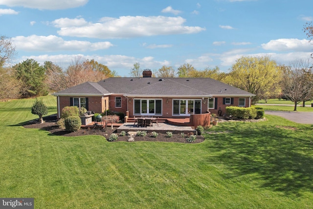 rear view of property featuring a patio area, brick siding, a yard, and a chimney