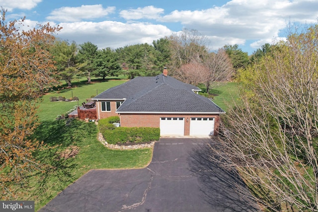 view of home's exterior with a shingled roof, a yard, a garage, aphalt driveway, and brick siding
