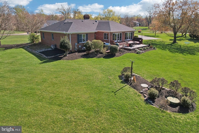 rear view of property with a patio area, brick siding, a yard, and a chimney