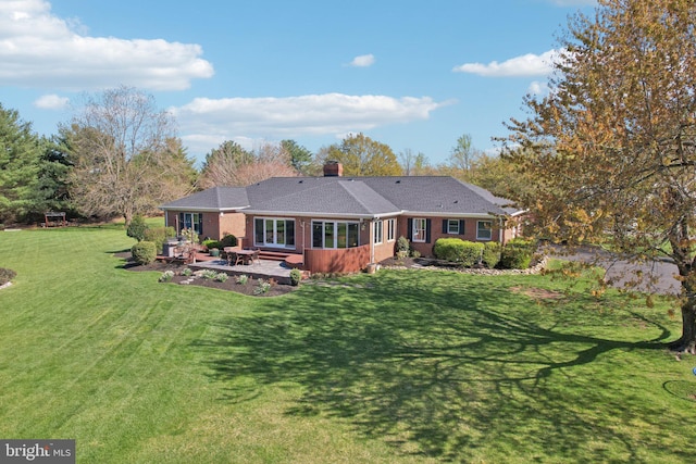rear view of house with brick siding, a yard, a patio area, and a chimney