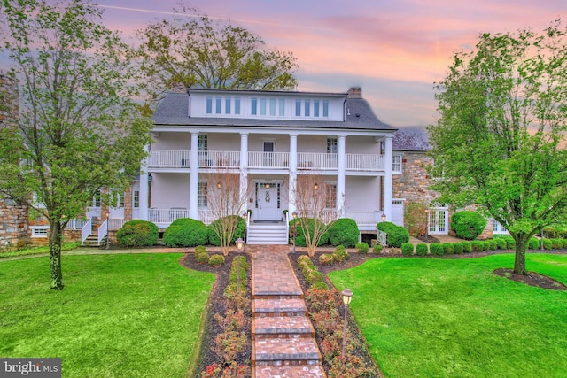 greek revival inspired property featuring a porch, a shingled roof, and a front lawn
