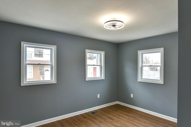 empty room with visible vents, baseboards, and wood finished floors