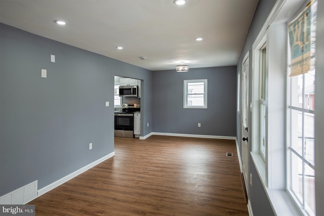 empty room featuring dark wood-type flooring, recessed lighting, visible vents, and baseboards