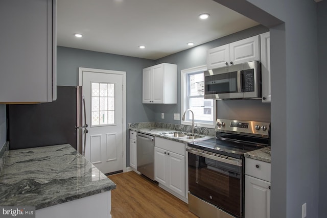 kitchen with appliances with stainless steel finishes, a sink, and white cabinetry