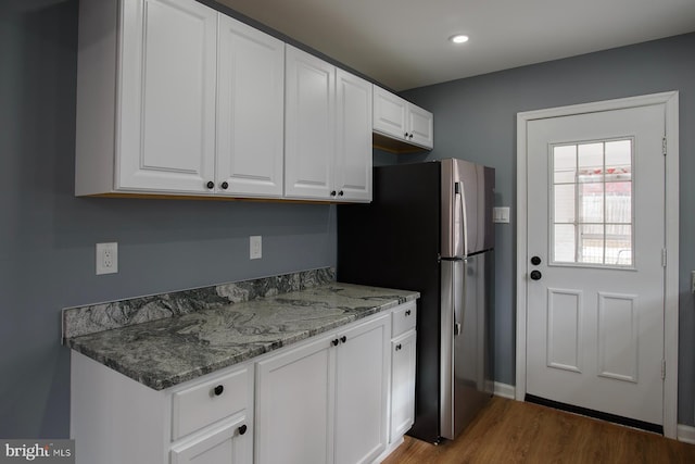 kitchen with dark wood-style floors, recessed lighting, freestanding refrigerator, white cabinets, and light stone countertops